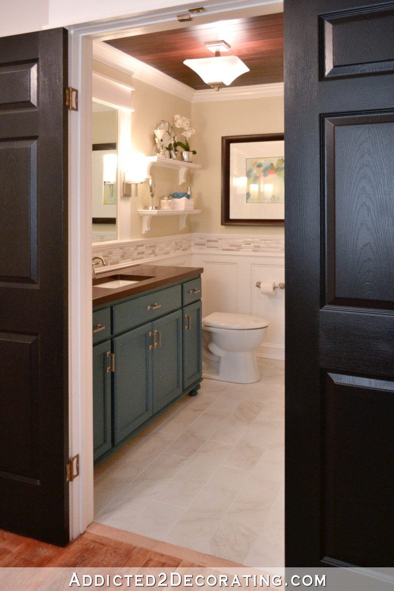Bathroom remodel with wainscoting, furniture-style vanity, wall sconces and shelves